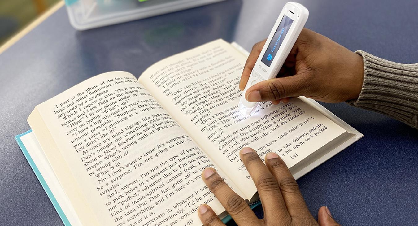 A person uses a C-Pen with a book.