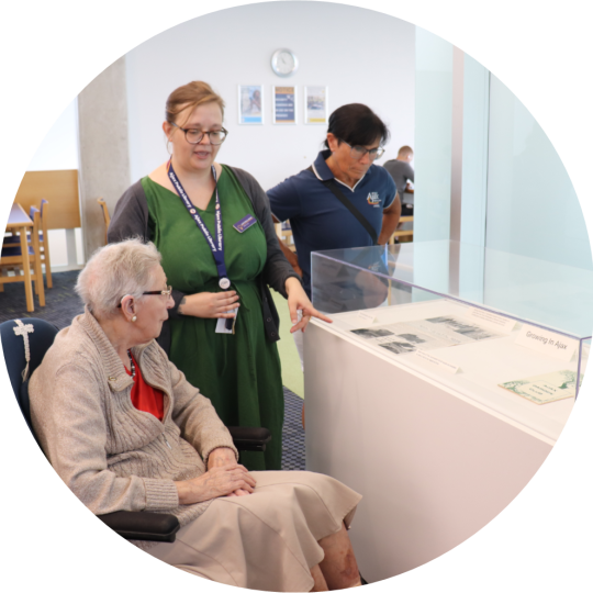 The Archives Services Librarian shows items on display to two people. 